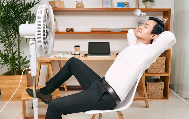 man cooling down with a standing fan