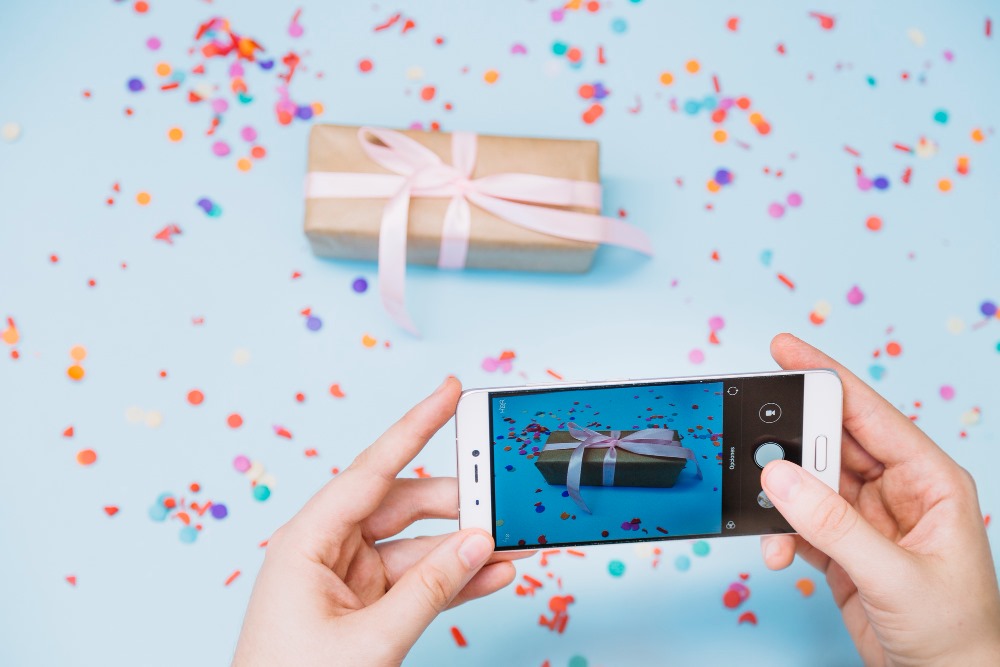 This photo depicts an individual taking a photo of a gift box with a smartphone.