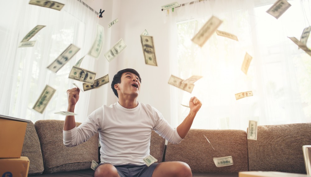 This photo depicts a man overjoyed with money falling and flying around him.