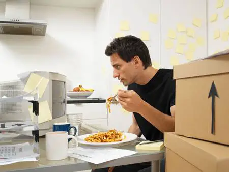 man eating in front of computer