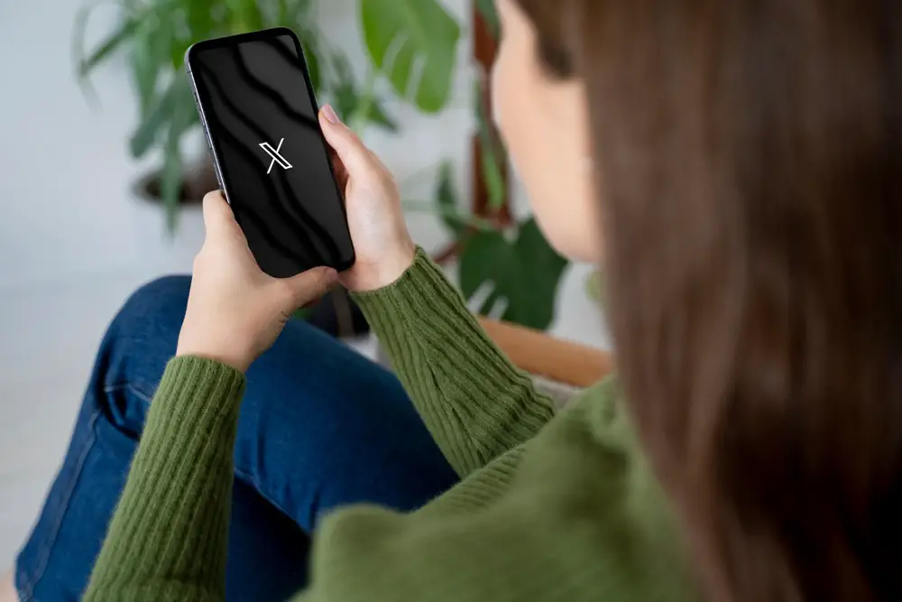 This photo shows a women is opening the X (Twitter) mobile app on her smartphone.