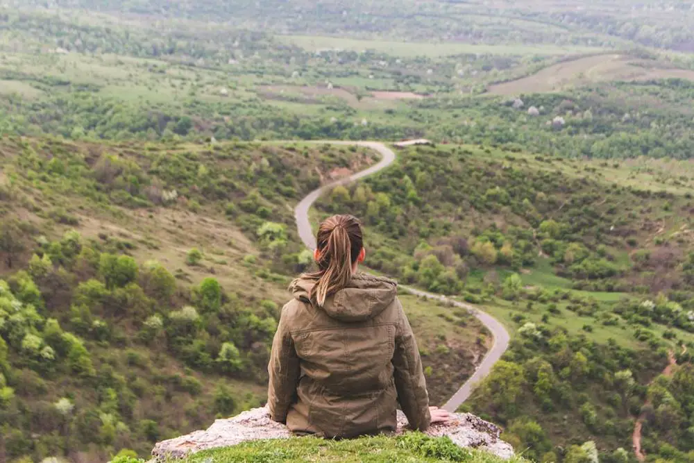 How to Use Relationship Mapping Effectively - This photo shows a girl is sitting on a cliff, overlooking a pathway.