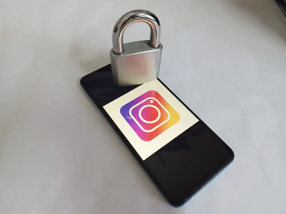How to Enable or Use End-to-End Encryption in Instagram Chats - This photo shows the Instagram logo appearing on a smartphone screen and a padlock is placed on top of the phone screen.