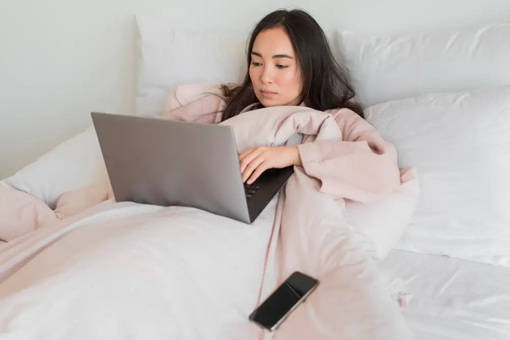 How gadgets affecting health - This photo shows a women lying on a bed using her laptop.