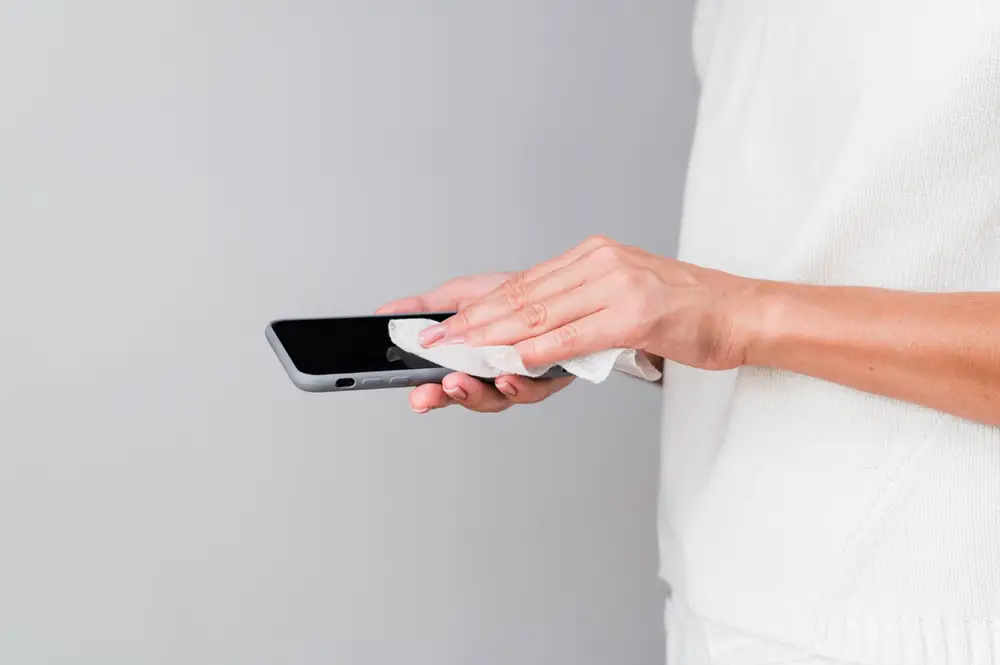 Using a piece of clean and dry cloth to wipe a smartphone.