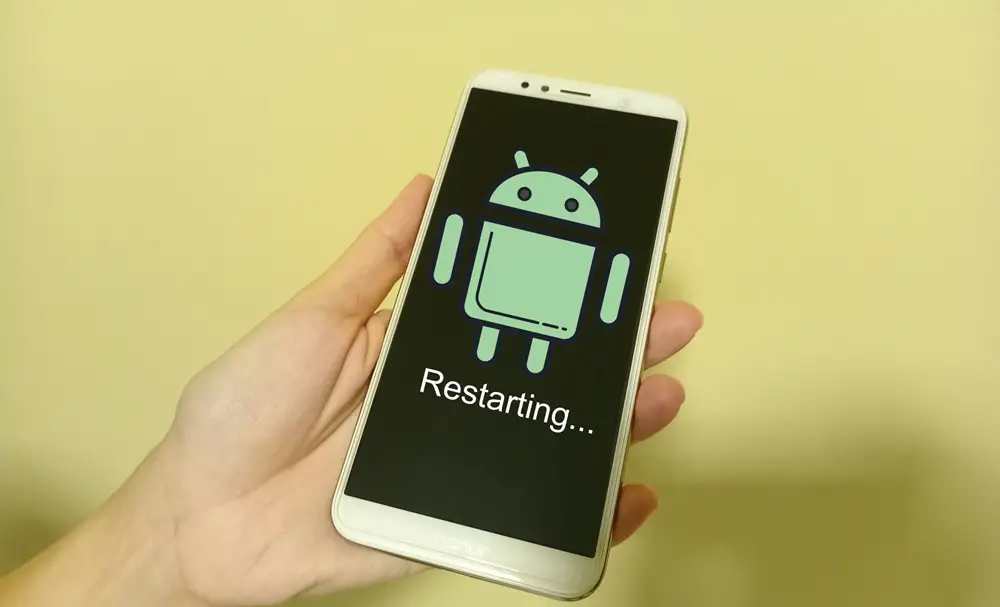 How to Fix an Android Phone That Keeps Restarting: This photo depicts a woman's hand holding an Android phone, its screen displaying the Android logo during a restart.