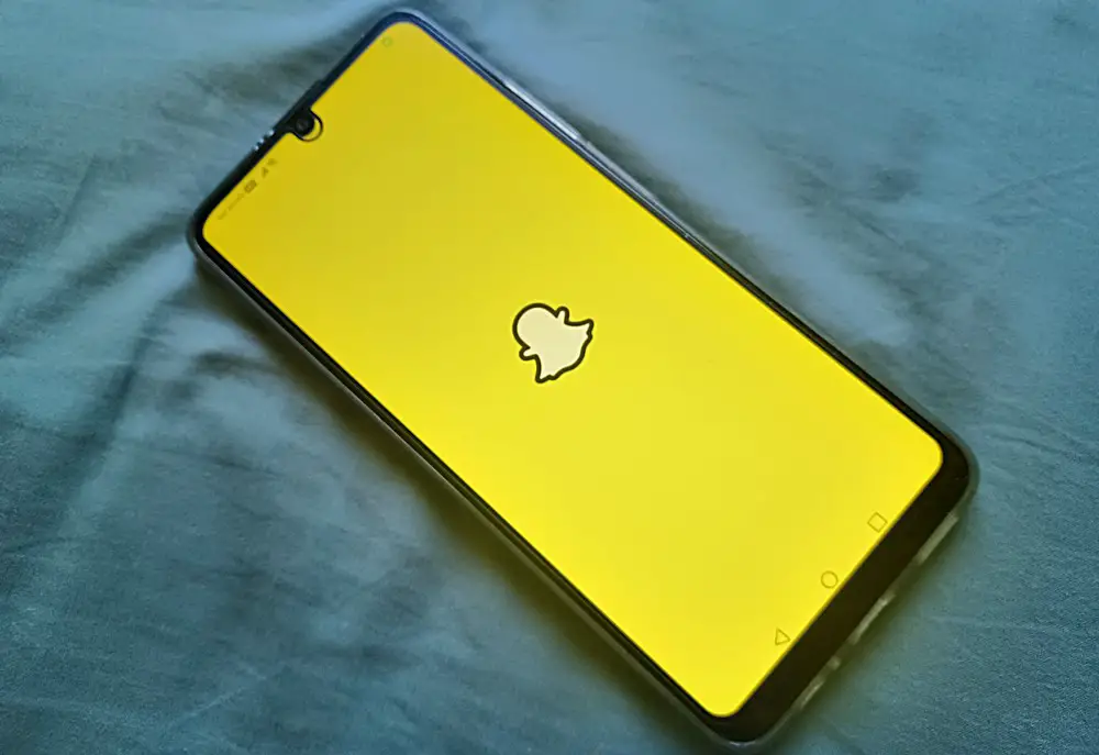 This photo shows a smartphone with its screen displaying the Snapchat logo.