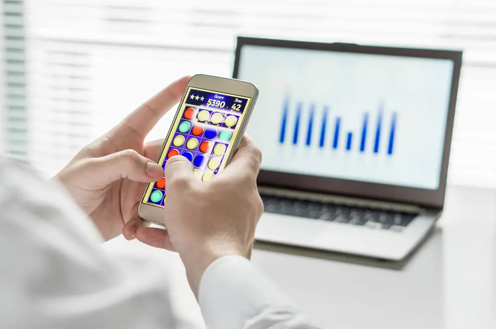 This photo depicts an office employee playing a classic mobile game on his smartphone.