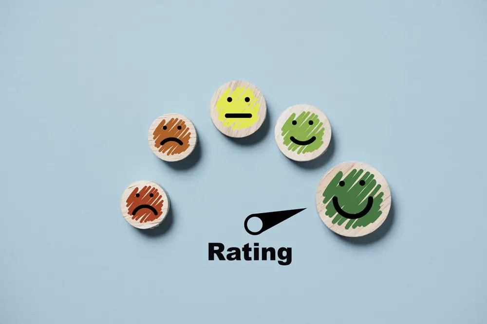 This image displays a customer evaluation indicator, showing ratings from low to high on wooden cube blocks. It's a print screen set against a blue background, representing the concept of client satisfaction after using a product or service.