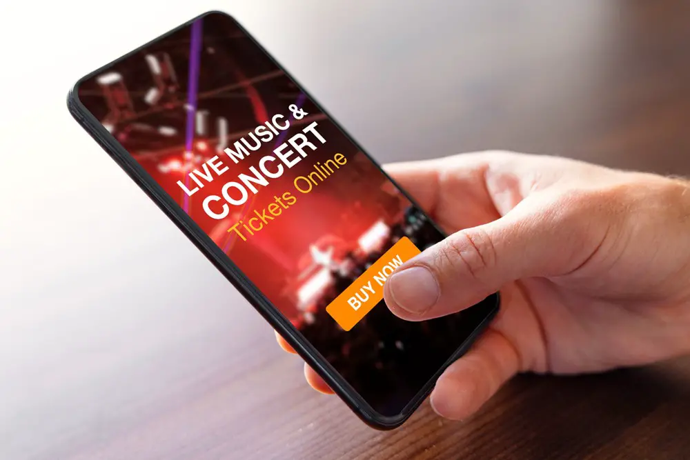 Lifehacks for Buying Tickets to Iconic Concerts & Events Abroad: This photo depicts a person buying music concert tickets online on mobile phone.
