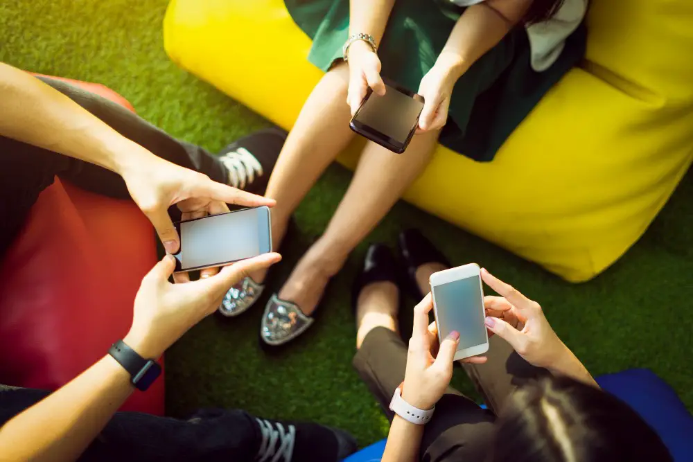 This photo depicts three young individuals sitting together engaging with their mobile phones.