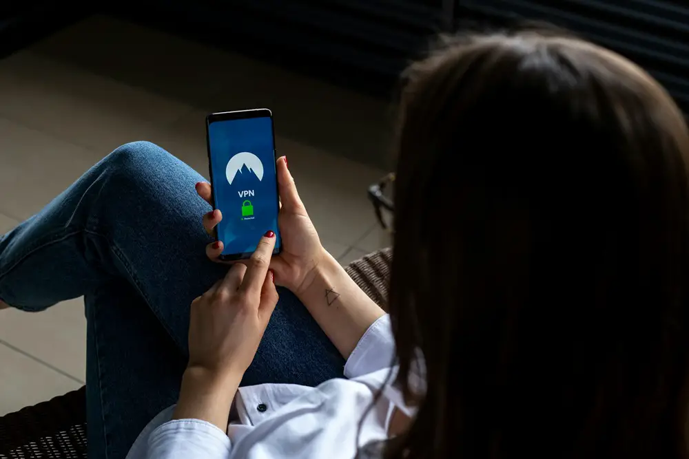 This photo depicts a woman turning on VPN and browsing the internet with her smartphone.