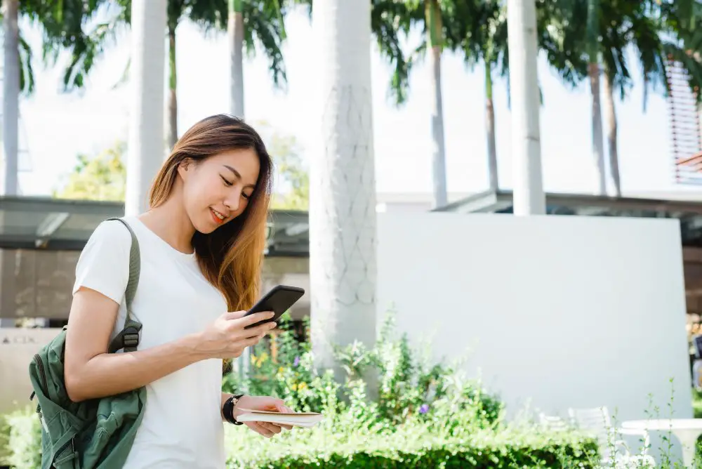 This photo depicts a woman tourist using her smartphone while traveling alone.