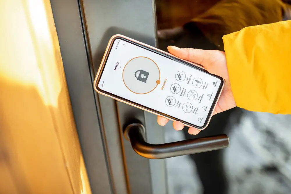 This photo depicts an individual remotely locking a smart lock on the entrance door using a smartphone, illustrating the concept of keyless access with smart electronic locks.