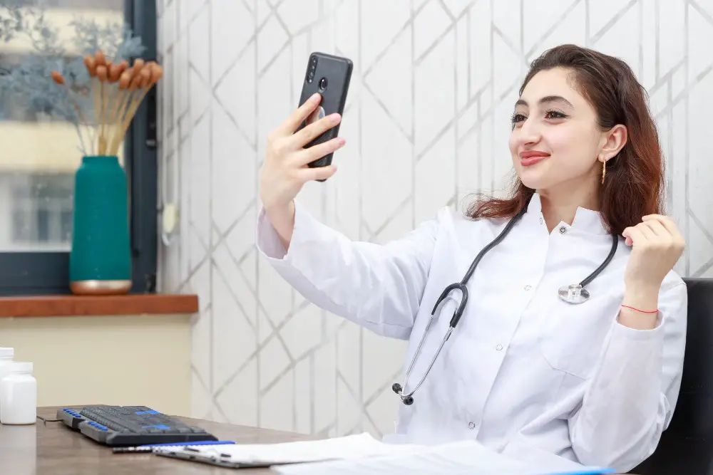 How Doctors are using Social Media and Technology: This photo shows a female doctor taking a selfie with her smartphone in her clinic.