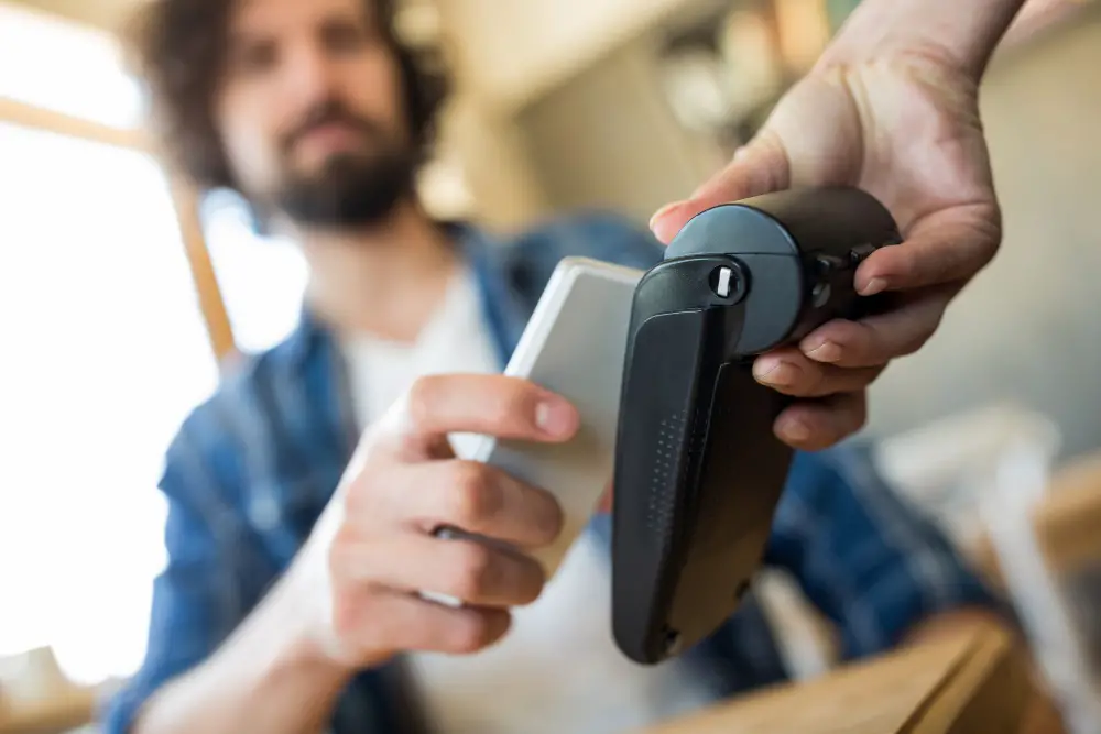 This photo depicts a man paying with NFC technology on his mobile phone.